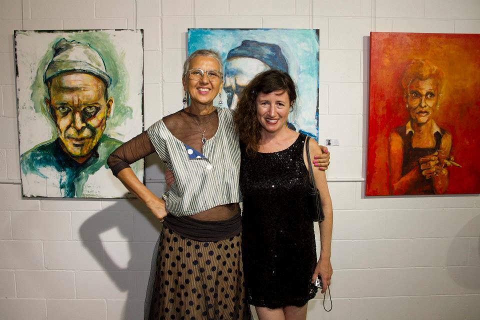 Dana Ellyn with 19 Karen Gallery owner, Terri Lew. Paintings of Matt Sesow by Dana Ellyn hanging at exhibit.
